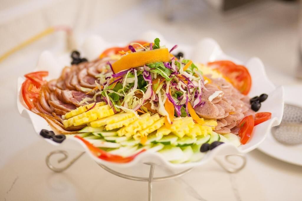 A colorful salad with various vegetables and meats on a white plate.