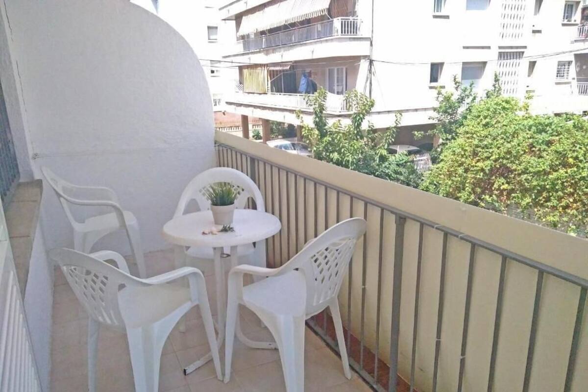 A balcony with a small round table and two white plastic chairs.