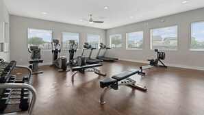 A spacious gym with various exercise equipment, large windows, and a ceiling fan. - Spacious 4BR w/ Yard, Near Airport & F1 Circuit in Quiet Neighborhood (Austin)