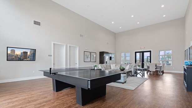 A spacious living room with a ping pong table, a dining area with a table and chairs, and a cityscape painting on the wall. - Spacious 4BR w/ Yard, Near Airport & F1 Circuit in Quiet Neighborhood (Austin)