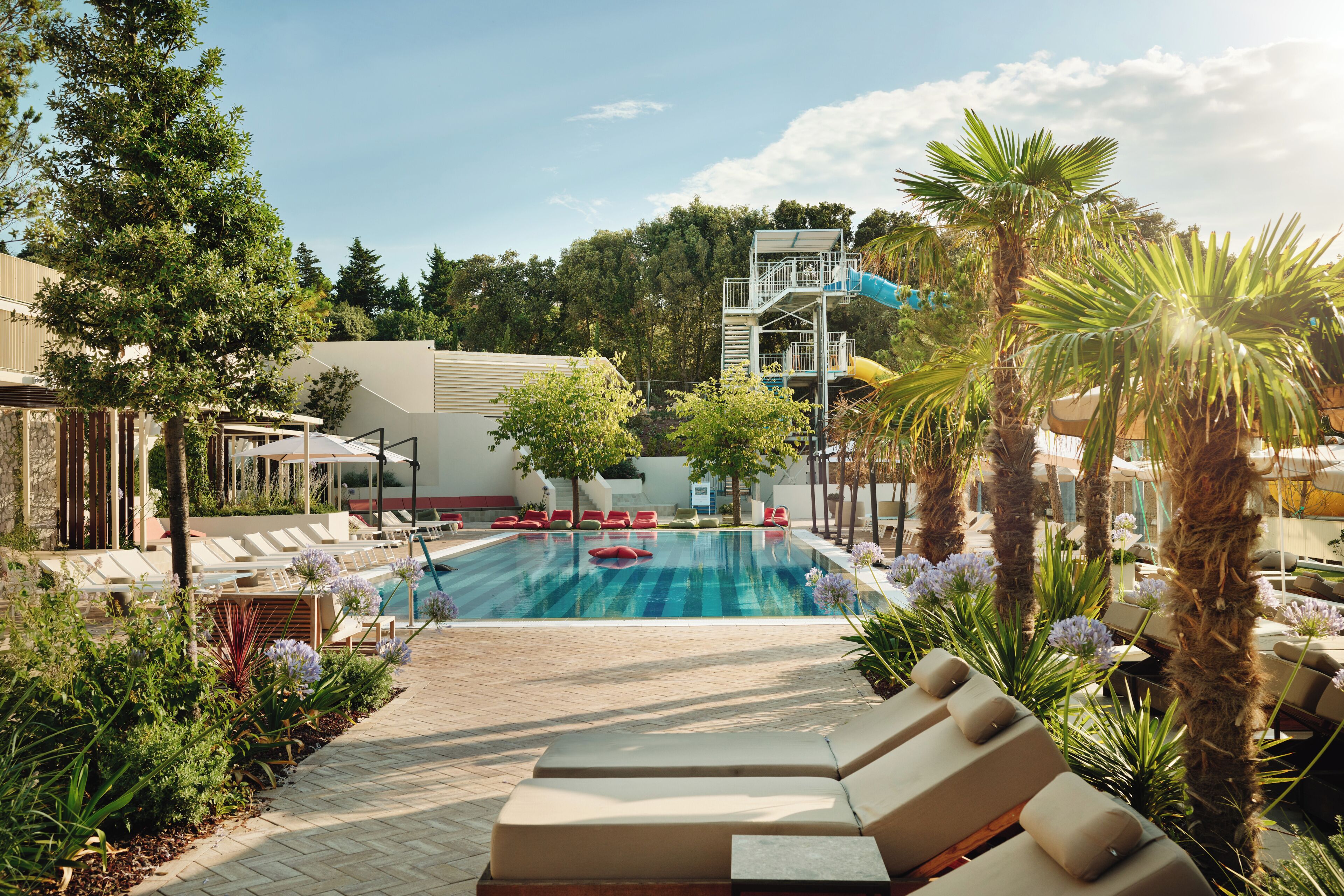 A pool area with lounge chairs and a water slide.