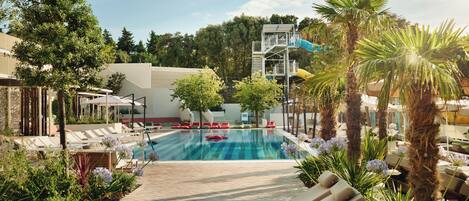 A pool area with lounge chairs and a water slide.