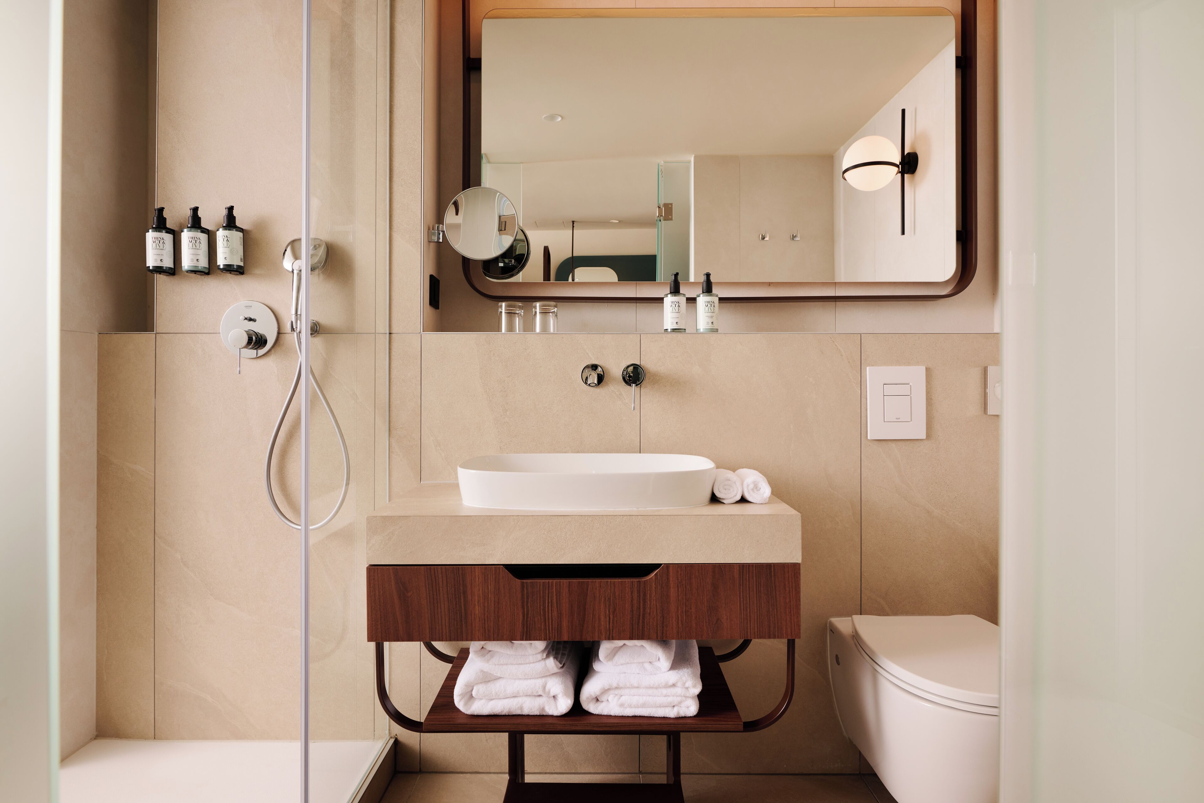 Ein modernes Badezimmer mit einem großen Spiegel, einem Waschbecken und einer Toilette.