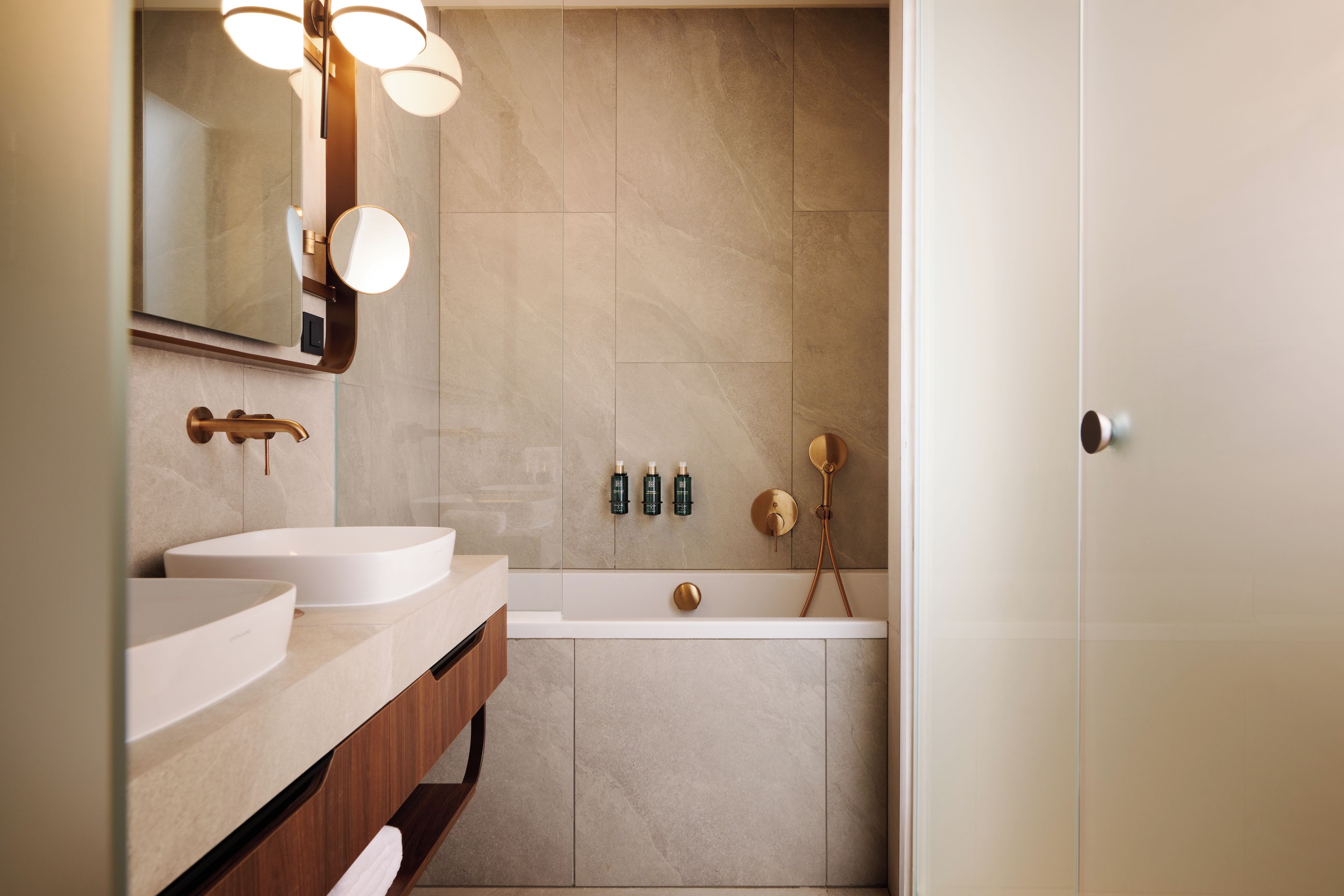 Un baño moderno con dos lavamanos, una bañera y una ducha.