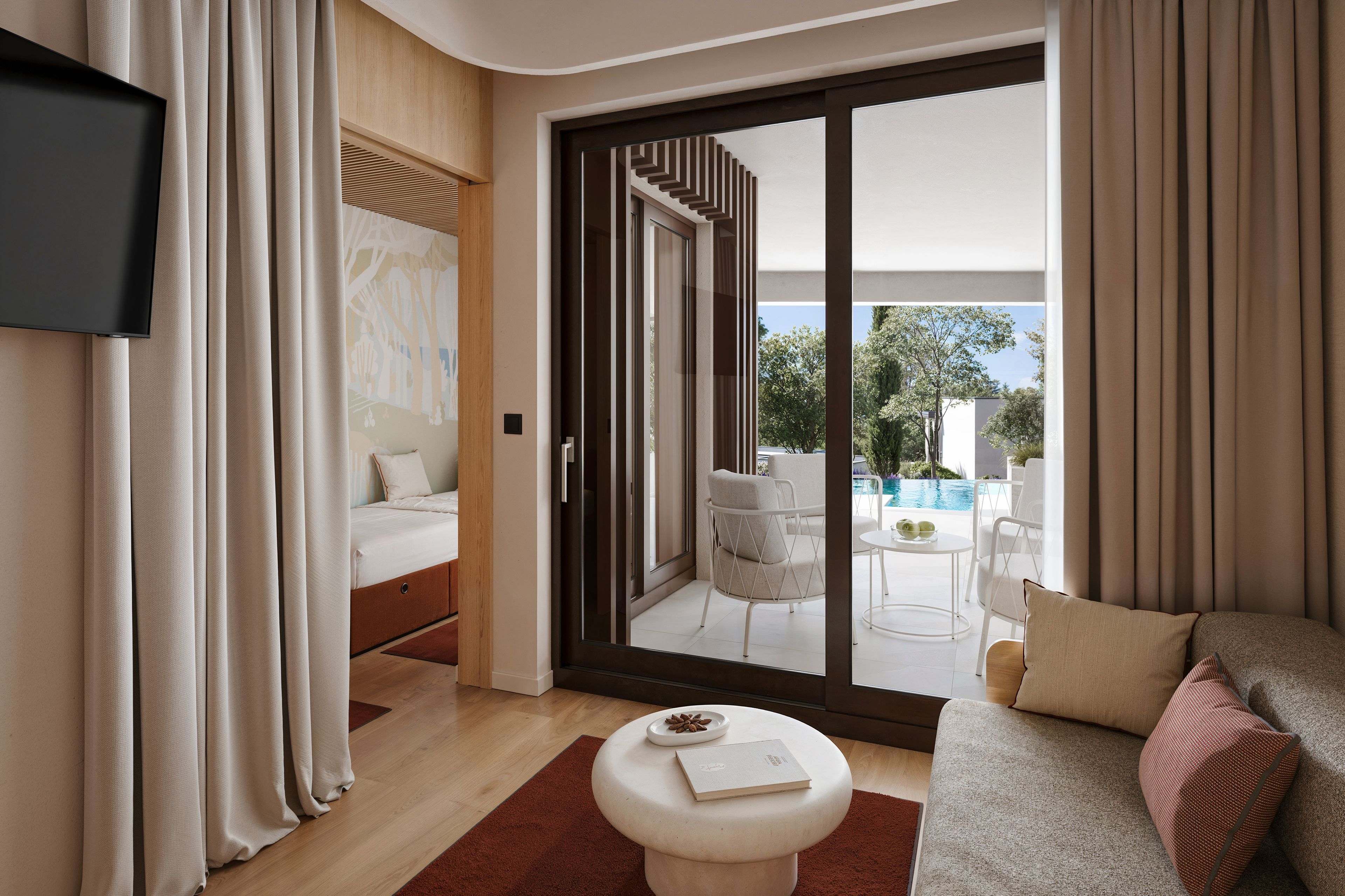 Una habitación de hotel moderna con cama, sofá, una mesita y puerta corrediza de vidrio que da a una zona de piscina.