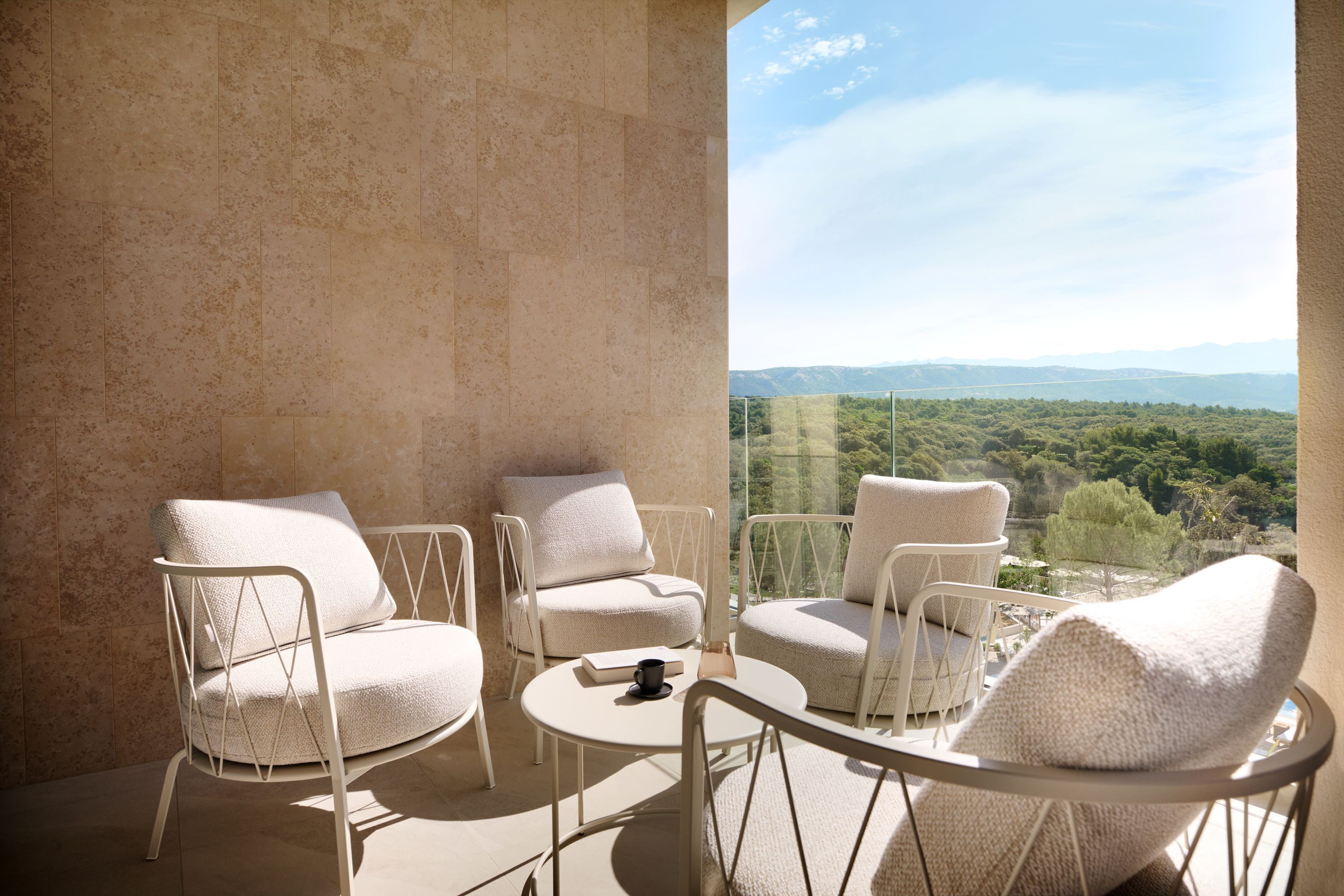Un balcon avec quatre chaises blanches et une petite table ronde, offrant une vue sur un paysage pittoresque.