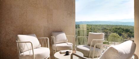 Un balcon avec quatre chaises blanches et une petite table ronde, offrant une vue sur un paysage pittoresque.
