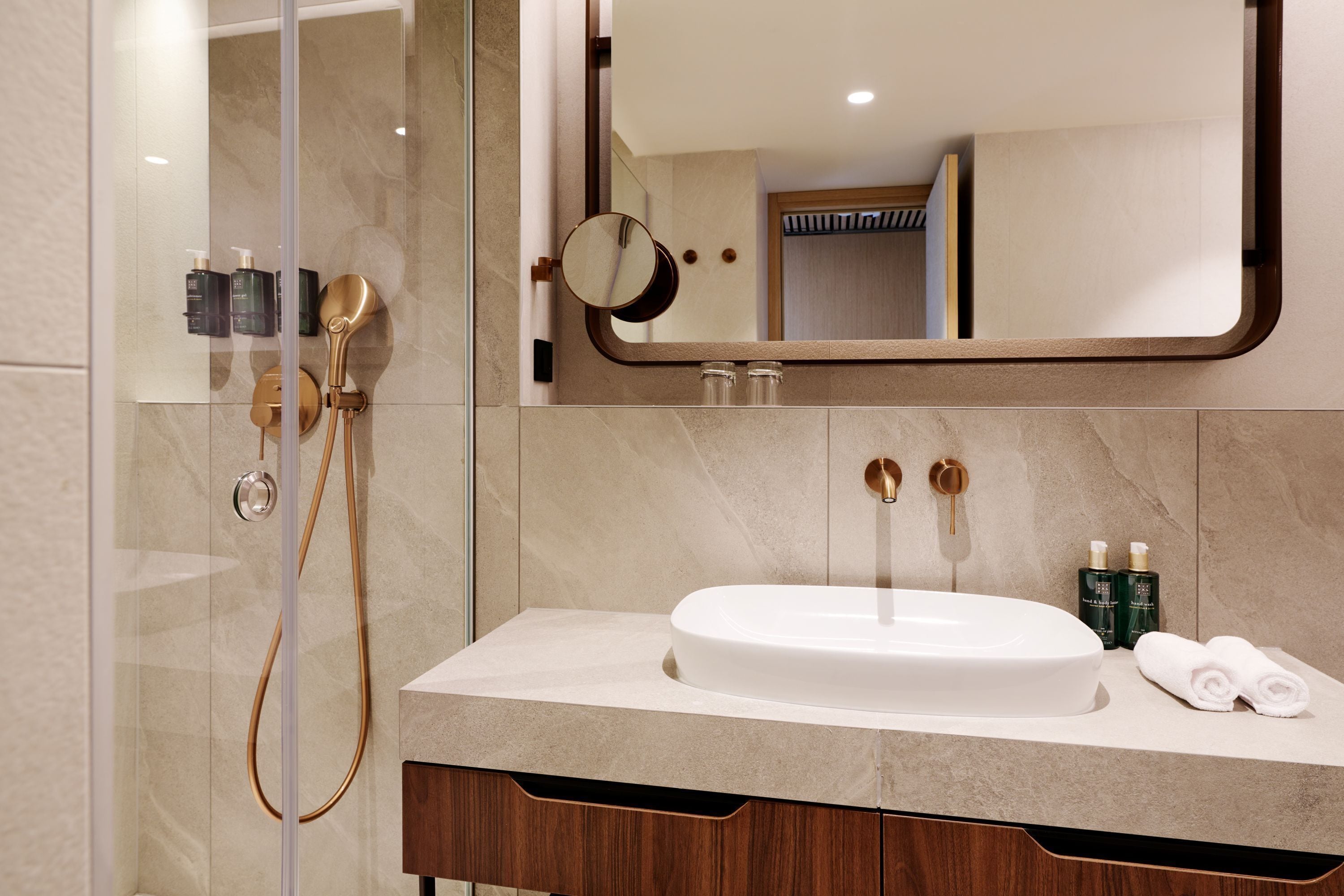 A modern bathroom with a glass-enclosed shower, a white sink, and a mirror.