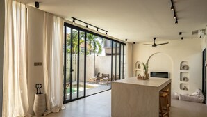 A modern kitchen with a central island, large sliding glass doors, and a ceiling fan. - Casanna Umalas (Kerobokan)