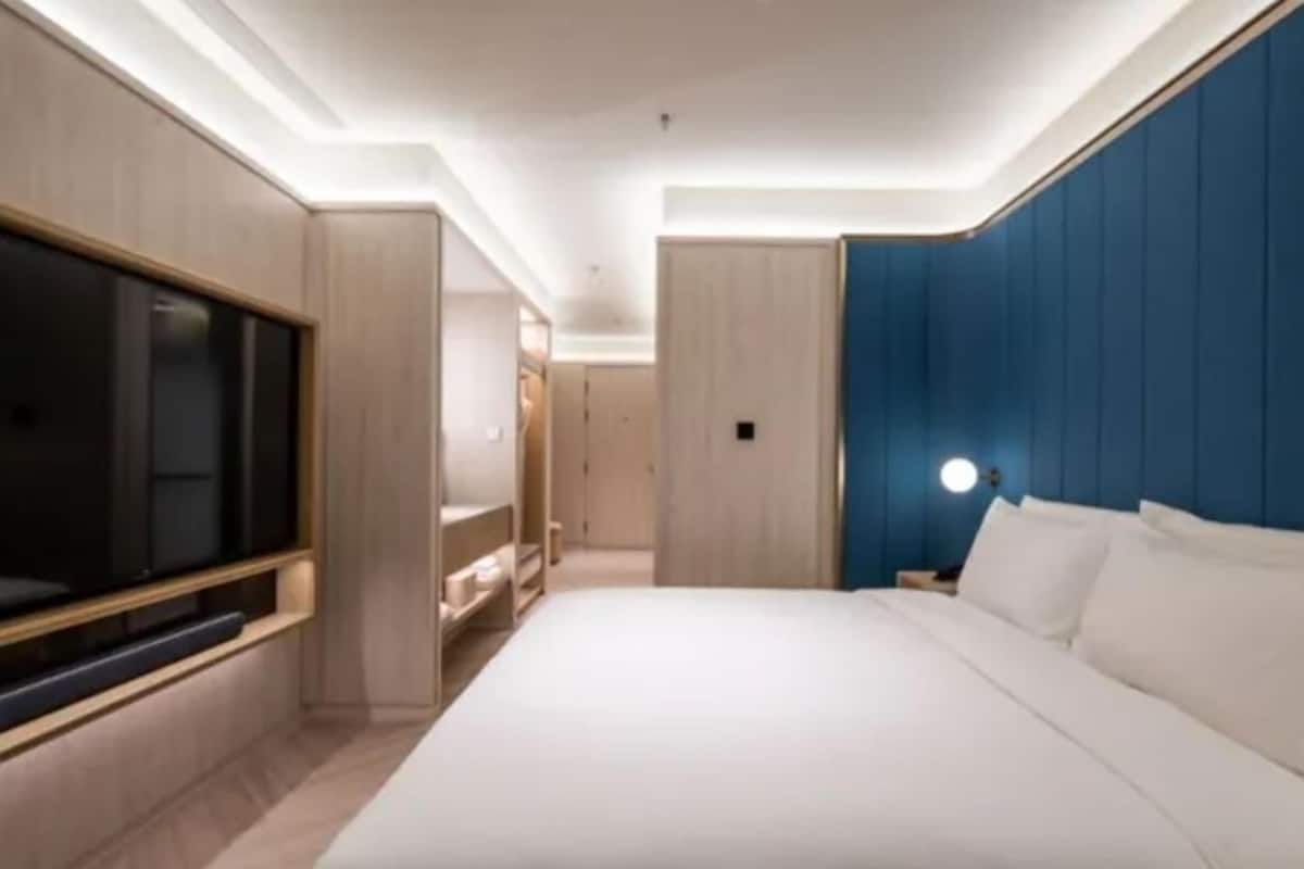 Habitación de hotel moderna con una cama grande, un televisor montado en la pared y una pared de acento azul.