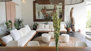 A modern living room with a sofa, round ottomans, and hanging pendant lights. - Umalas 5BR Bohemian Escape • Rice Fields + Yoga & Spa w/ 12min To Beach (Badung)