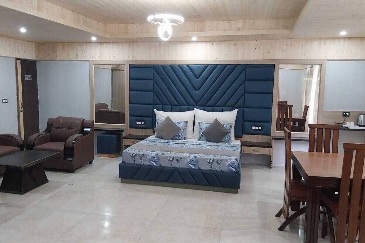 A modern bedroom with a large bed, a sofa, a coffee table, and a dining area.