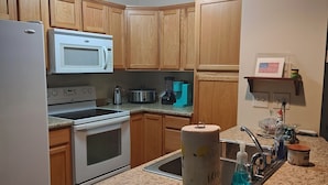 Una cocina con armarios de madera, microondas, estufa y un lavamanos.