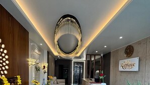 A modern hotel lobby with a reception desk, a chandelier, and a clock on the wall. - Hotel Ramaye - Bhopal (Bhopal)