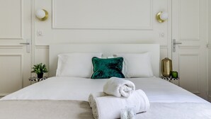 Ein Hotelzimmer mit einem ordentlich bezogenen Bett, weißen Wänden und einem grünen Kissen.