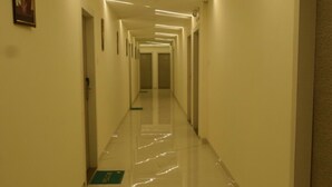 A long, well-lit hallway with a shiny floor, leading to a door at the end. - HOTEL MAGNET - INDORE (Indore)