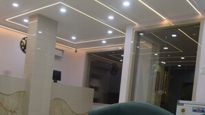 A modern reception area with a white reception desk, green seating, and a marble floor. - HOTEL MAGNET - INDORE (Indore)