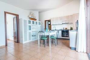 A kitchen with a dining table, chairs, cabinets, and a ship model on the wall. - Villa Laura (Arzachena)