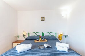 A neatly made bed with a tray of croissants, a book, and towels. - Villa Laura (Arzachena)