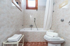 A bathroom with a bathtub, toilet, and a towel rack. - Villa Laura (Arzachena)