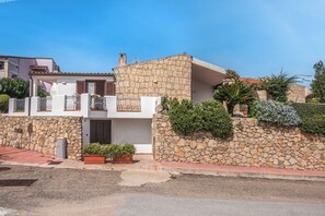 A two-story house with a stone facade, a balcony, and a small garden area. - Villa Laura (Arzachena)