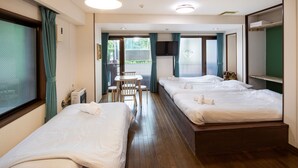 Ein Hotelzimmer mit zwei Betten, einem kleinen Tisch, Stühlen und Blick auf Grünfläche.