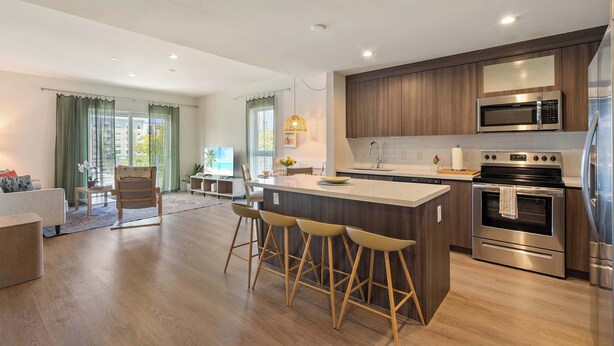 A modern kitchen with a central island, bar stools, stainless steel appliances, and a view to the living area. - Bright Hollywood Two Bedroom with Free Parking (Hollywood)