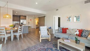 A modern living space with a dining area, kitchen, and a sofa with red cushions. - Bright Hollywood Two Bedroom with Free Parking (Hollywood)