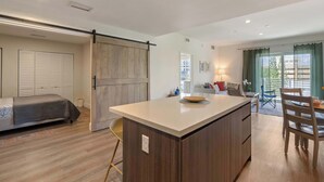 A modern kitchen with a central island, a dining area with a table and chairs, a sofa, and a sliding door closet. - Bright Hollywood Two Bedroom with Free Parking (Hollywood)