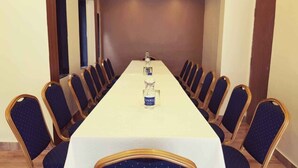 Une salle de conférence avec une longue table, des chaises et une bouteille d’eau posée sur la table.
