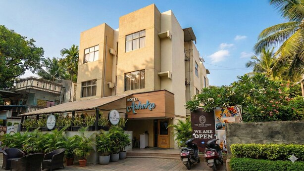 Un hôtel appelé Ashoka, doté d’un design moderne, d’une entrée couverte et d’une enseigne indiquant qu’il est ouvert.