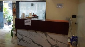 Un comptoir d’accueil avec un plateau en marbre et une enseigne indiquant « ASHOKA HOSPITALITY ».