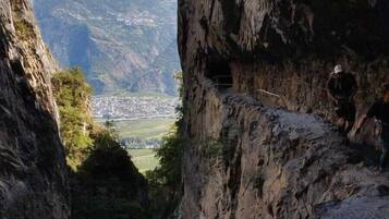 A narrow canyon with a view of a valley and distant mountains.