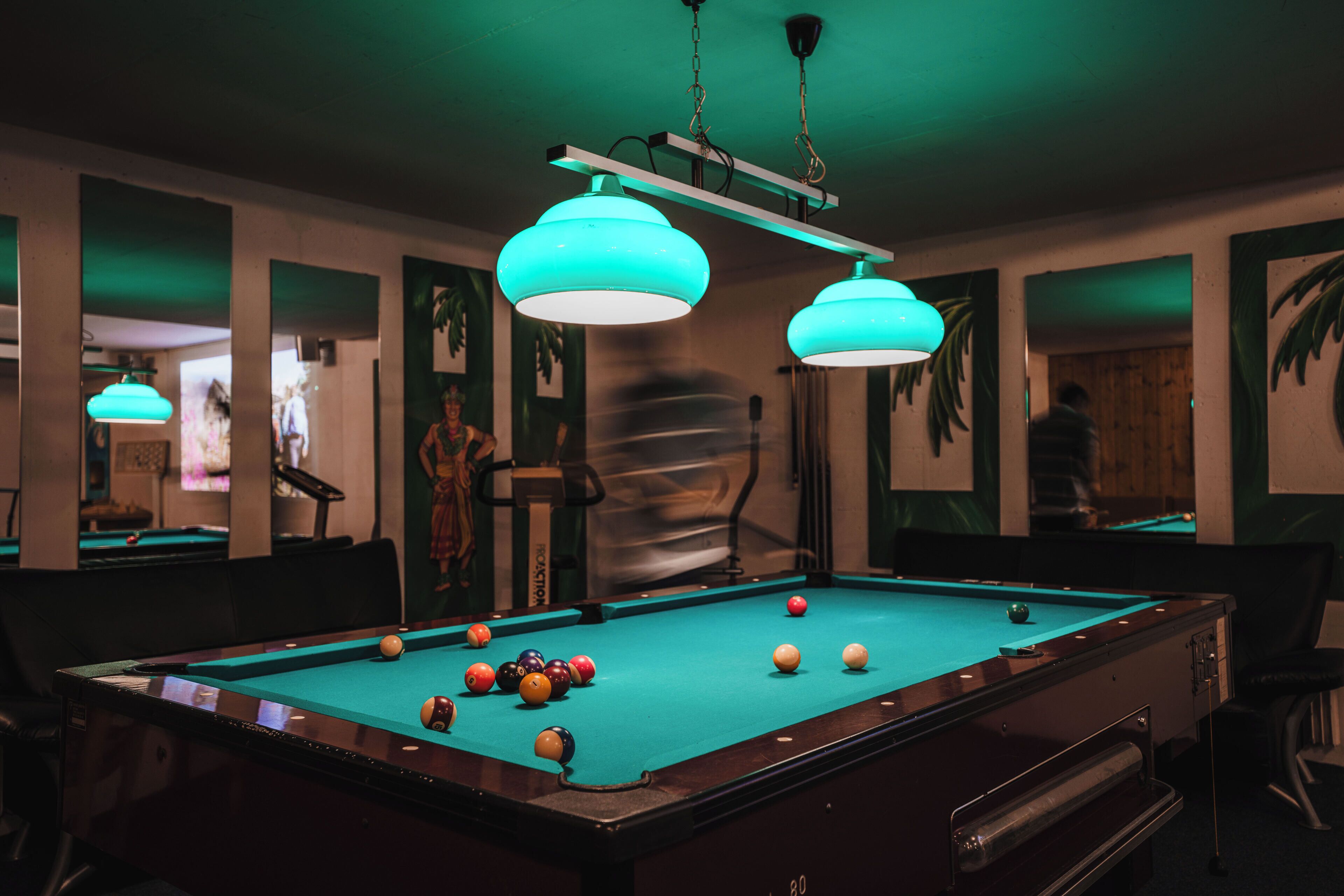 A pool table with balls, a bar area, and a person in the background.