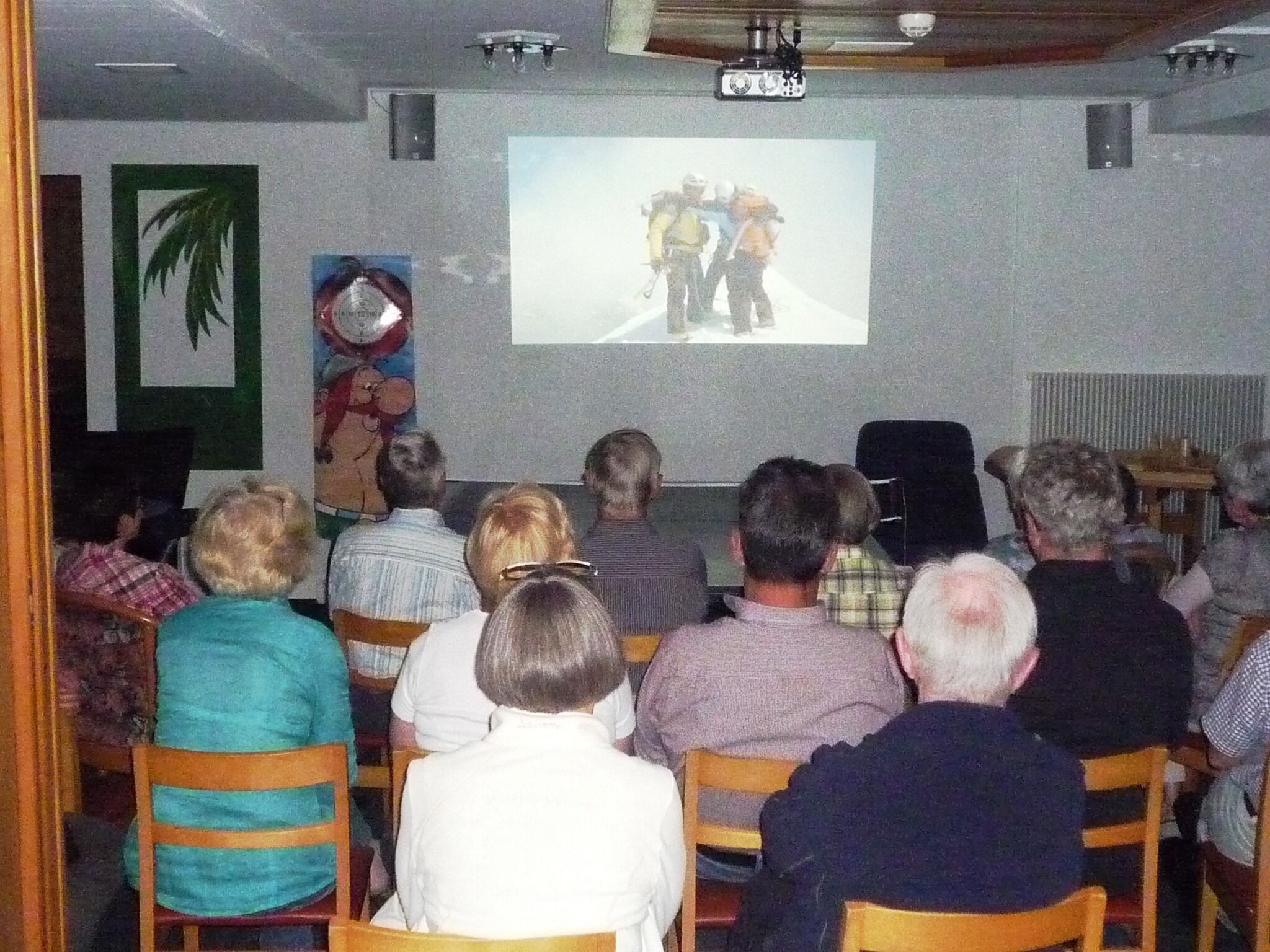 Un grupo de personas sentadas en una sala viendo una presentación.