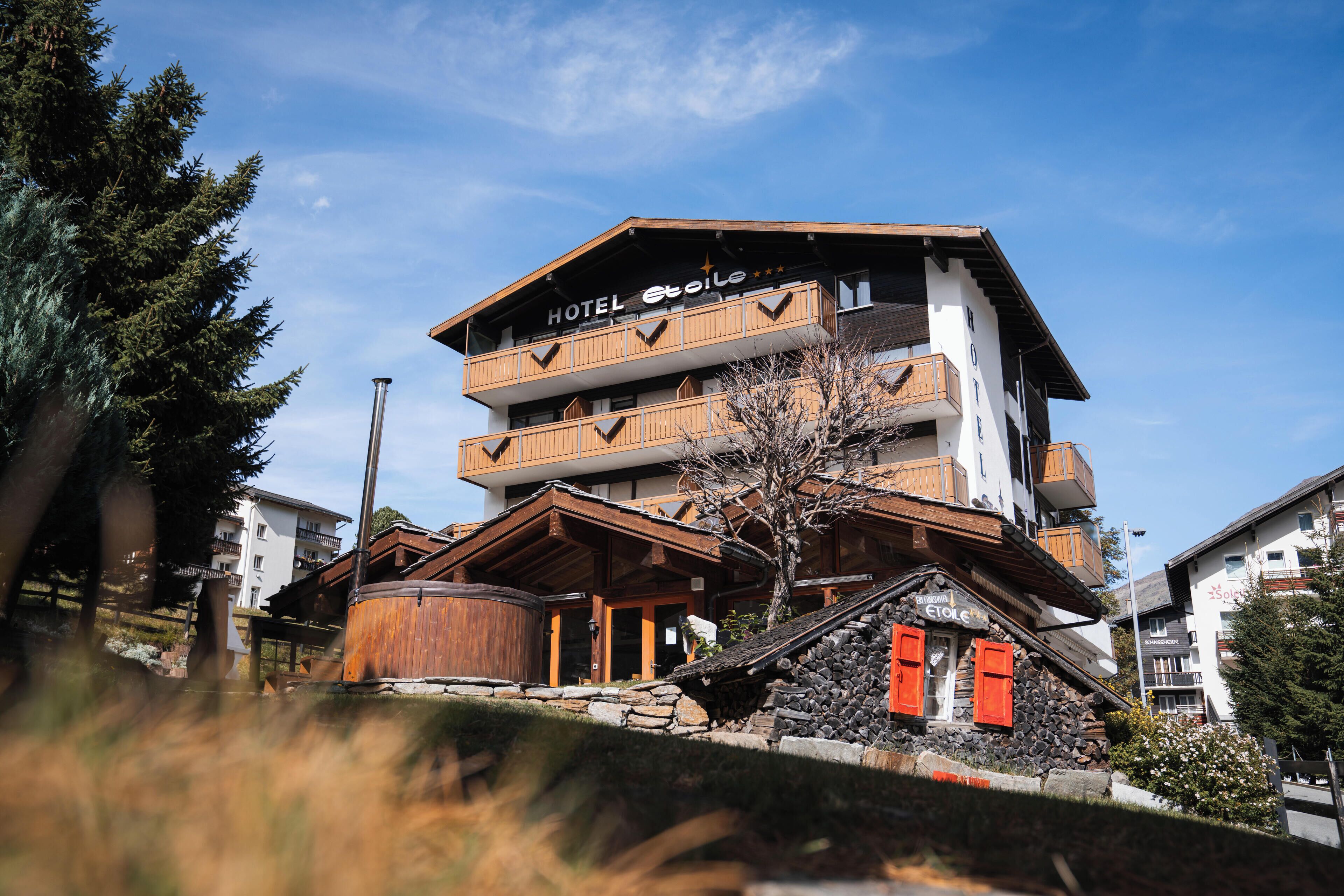 A multi-story hotel with a wooden facade, balconies, and a stone base.