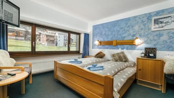 Un dormitorio con cama de madera, una mesita de noche, una silla, una ventana con vistas a edificios y un cuadro en la pared.