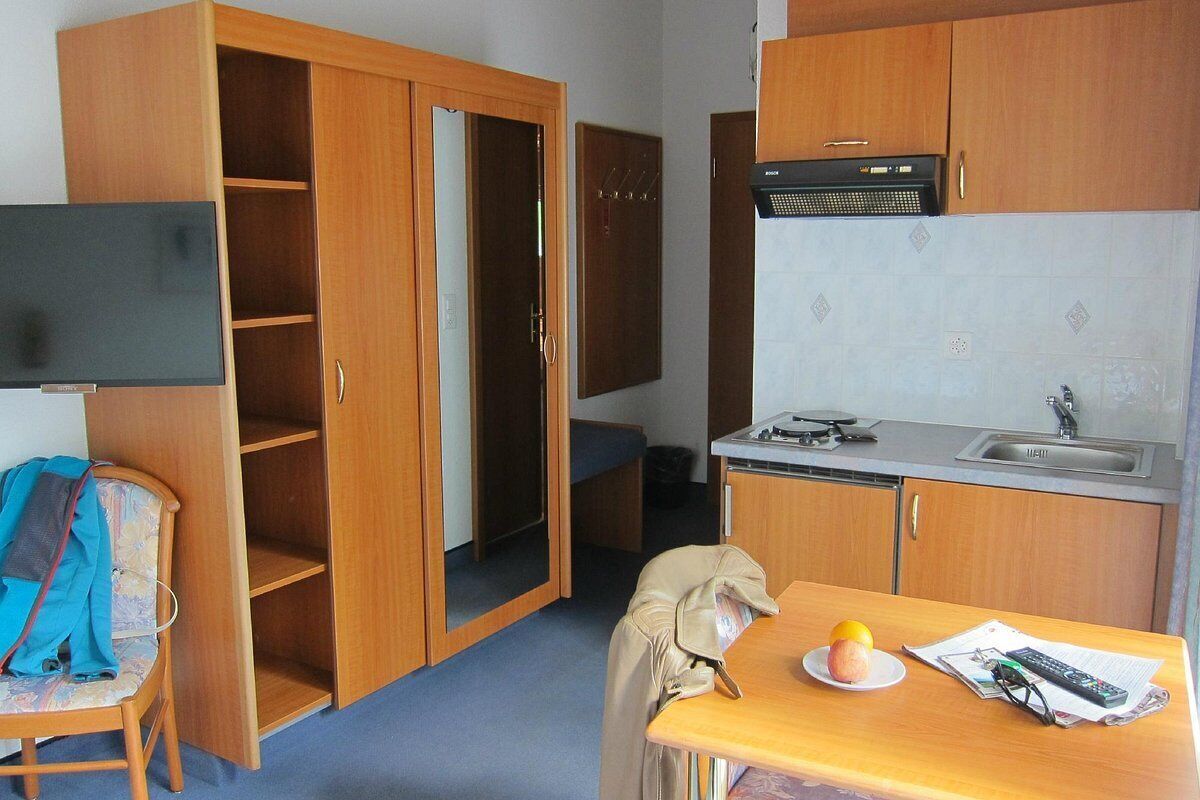 Una cocina compacta con armarios de madera, un microondas integrado y un lavamanos.
