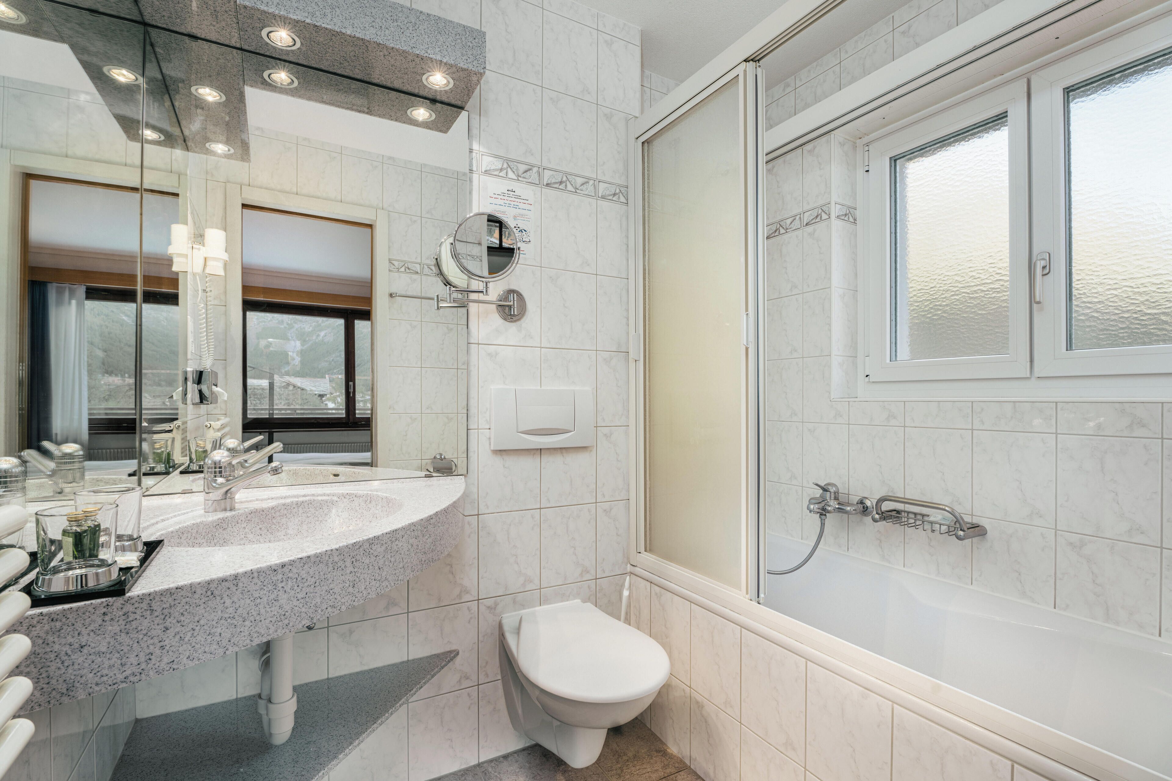Un baño moderno con lavabo de granito, inodoro y ducha a ras de suelo.