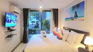 Ein Hotelzimmer mit Bett, Fernseher, einem Gemälde und Blick ins Freie.