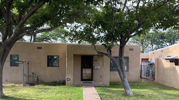 A building with a beige exterior, a door with the number 7433, and a sidewalk leading to the entrance. - Charming 2-bedroom house with AC, WiFi, walking distance from UPTOWN! (Albuquerque)