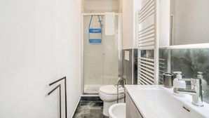 Een moderne badkamer met een douche, toilet en wastafel.