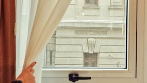 A window with a view of a building's facade, including a door and a window with a handle.