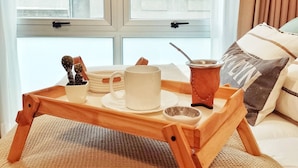 A cozy room with a large window, a wooden tray with a mug and a cup, and a small cactus plant.