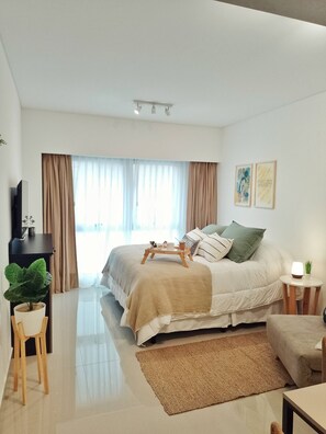 A modern bedroom with a bed, bedside table, lamp, and a large window with curtains. - Modern Studio at the Heart of San Telmo With Pool (Buenos Aires)