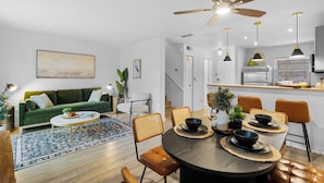 A modern living room with a green sofa, a dining table with chairs, and a ceiling fan. - Stop Scrolling - FREE Water Park Access - Newly Renovated Family Resort Home (Kissimmee)