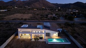 Una casa moderna con piscina, rodeada de paisaje desértico y montañas.