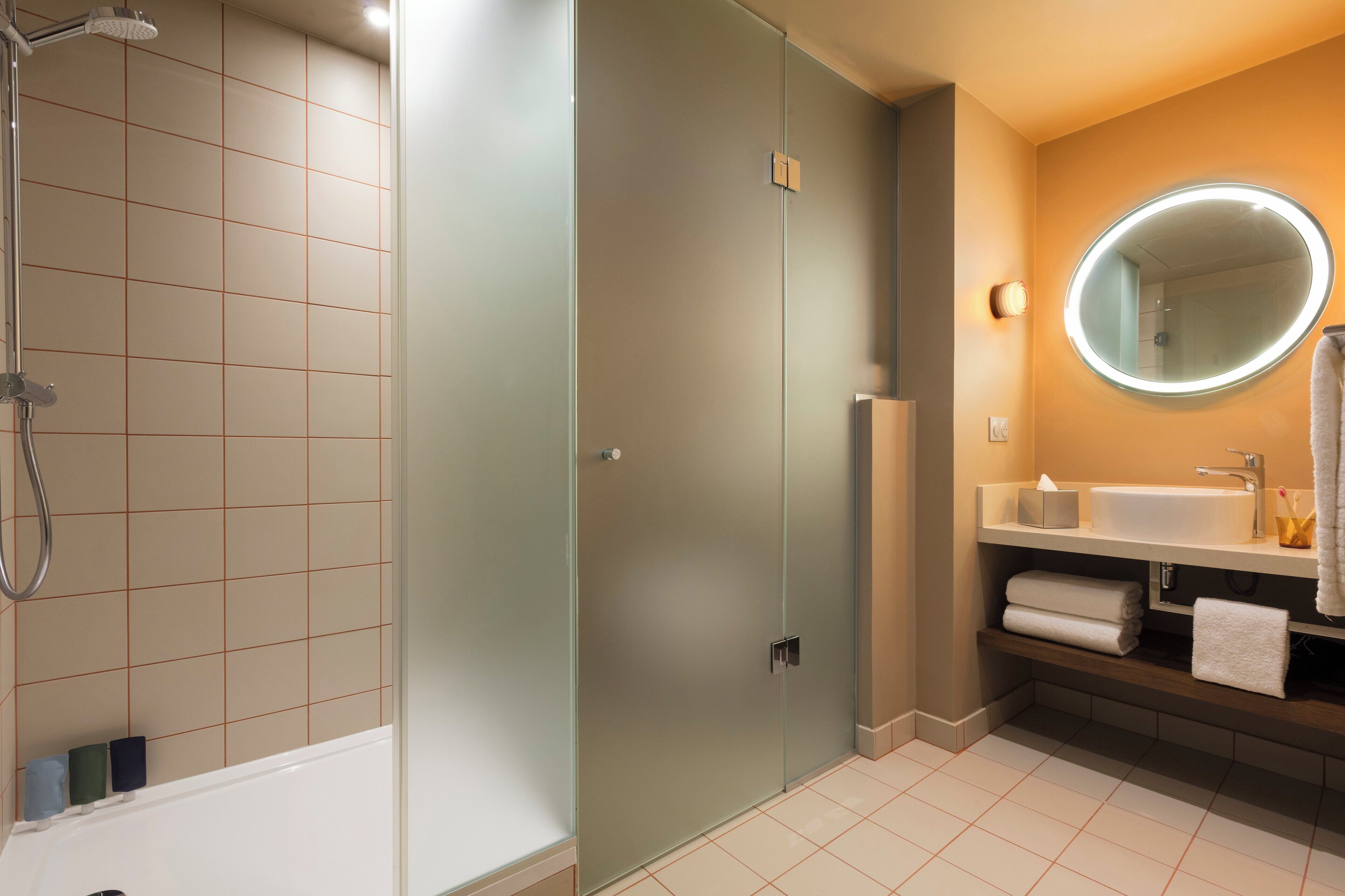 Ein modernes Badezimmer mit einer Duschkabine, einem Waschtisch inklusive Spiegel und einer Badewanne.