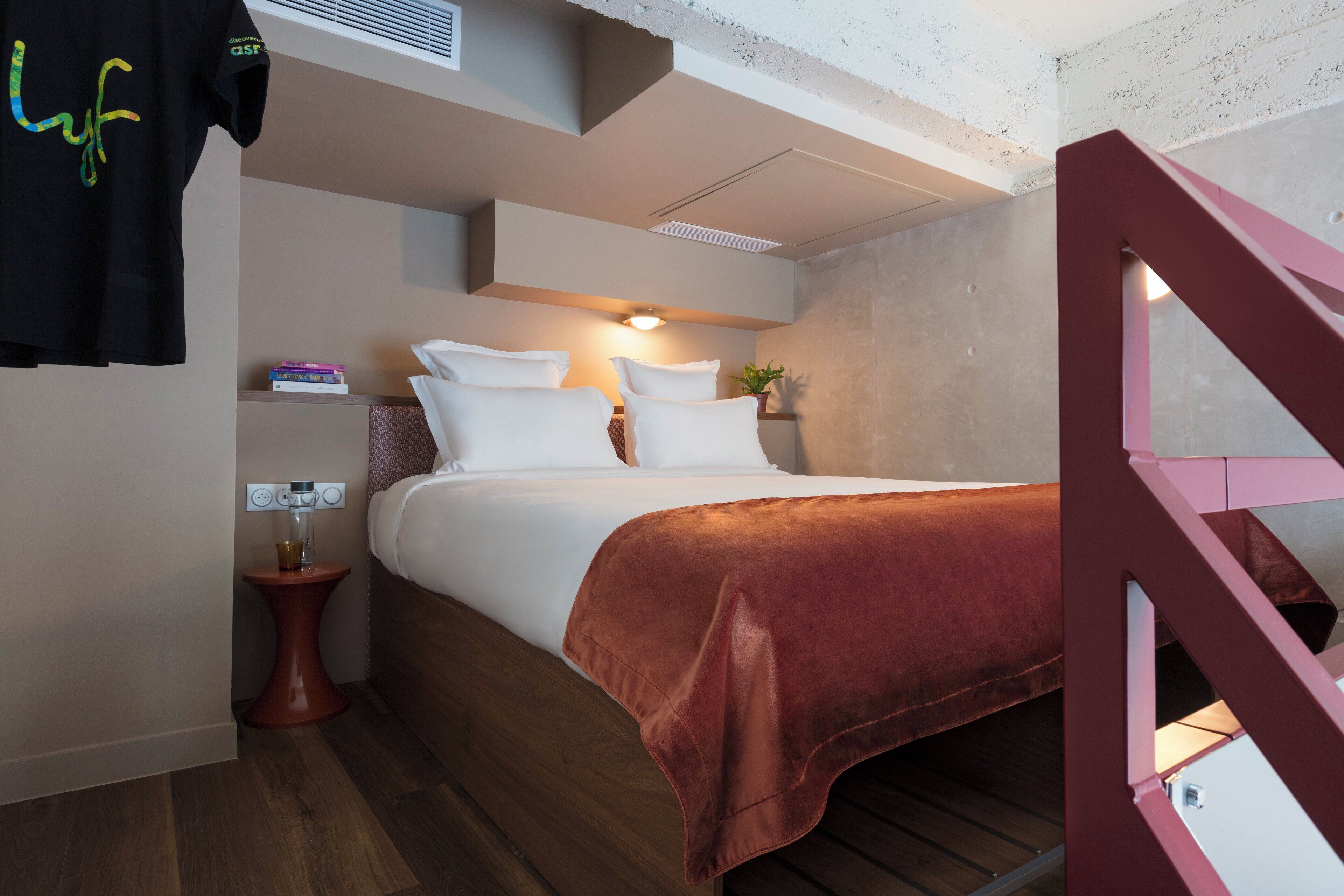 Une chambre à coucher moderne avec un lit, une table de chevet et un escalier rouge.