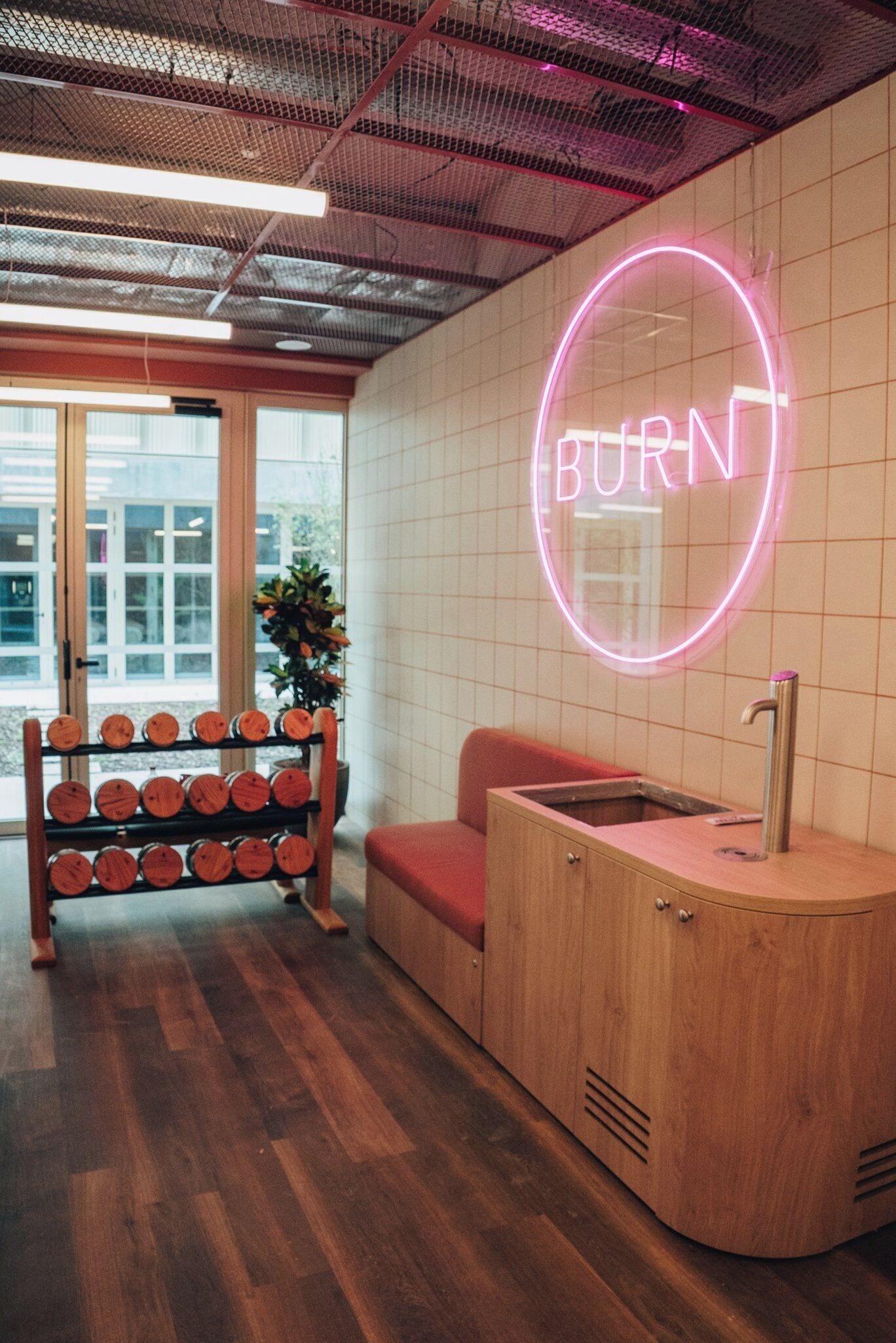 A modern bathroom with a neon sign, wooden cabinets, and a bench.